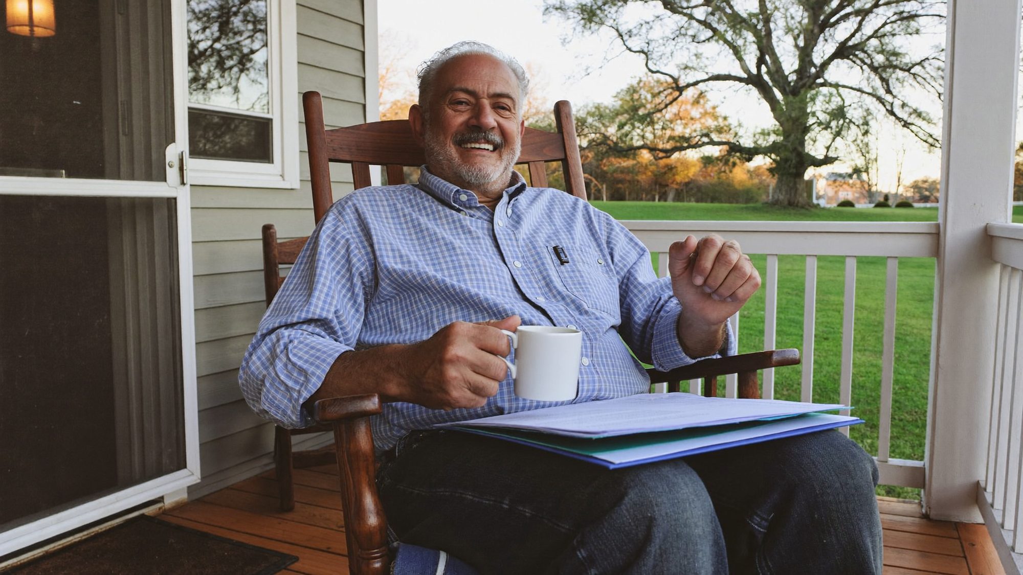 Retired man reviewing his retirement withdrawal plan on the front porch of his rural Georgia home in warm evening light